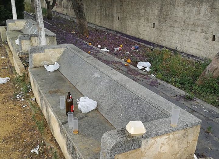 Basura acumulada en los bancos de calle la Feria en Santiponce.